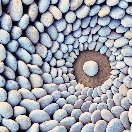 Smooth river rocks arranged in concentric circles around one center stone